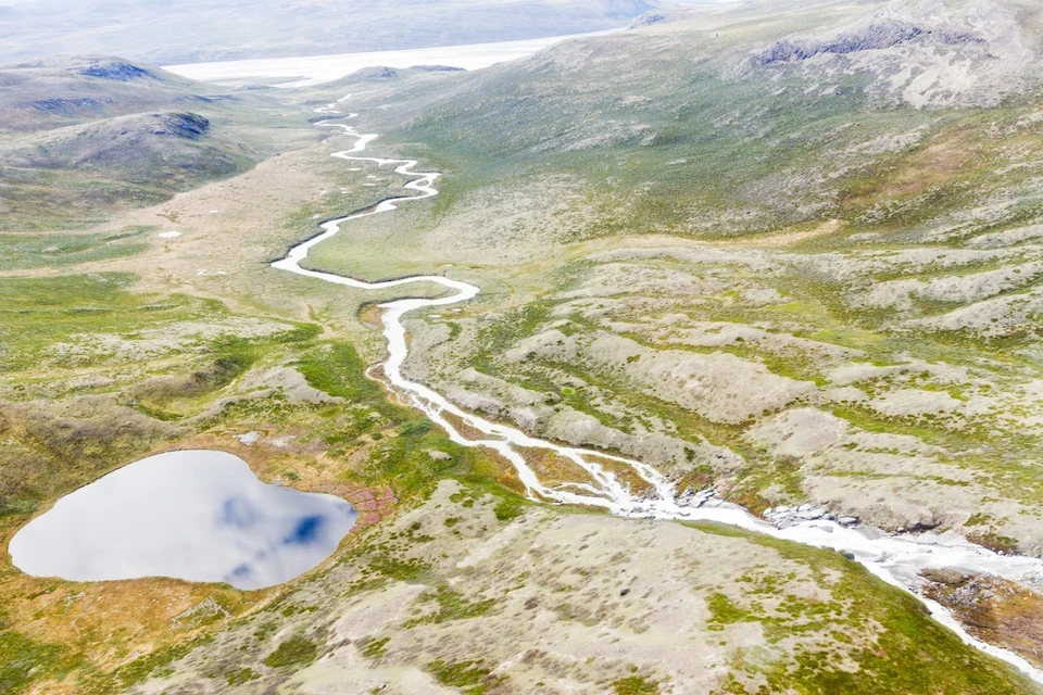 A mostly green and brownish landscape with a lake and a winding river