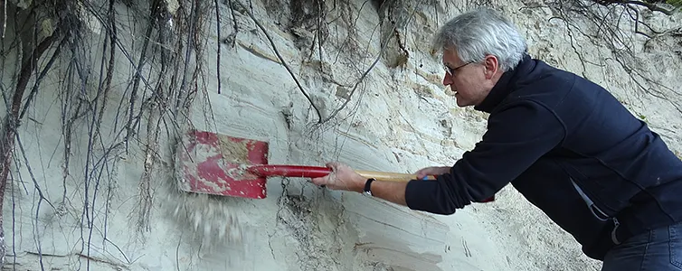 mand med skovl, som arbejder i sandbunke 