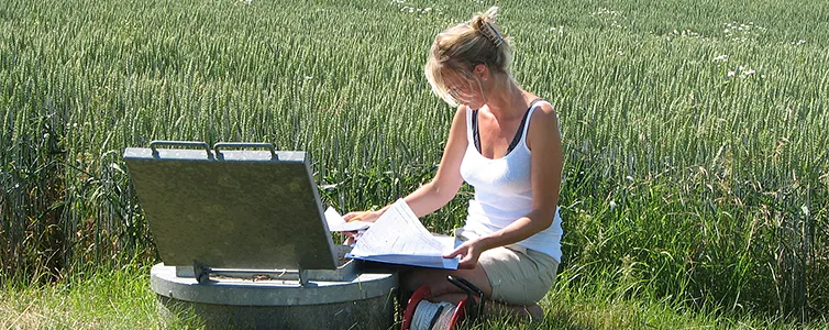 kvinde kigger på papirer ved en mark