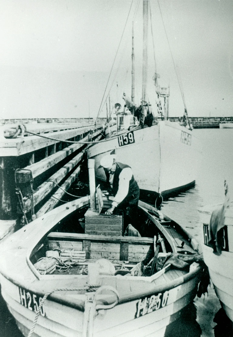 Niels Clausen i sin fiskerbåd Vi-To. Båden havde han fået bygget på skibsværftet Ferdinandsen og Andersen i Gilleleje for de penge, han fik i erstatning, da han mistede sit ben i en arbejdsulykke som sømand. Det var i denne lille jolle, at Clausen sejlede familierne Kublitz og Flanbaum til Sverige.