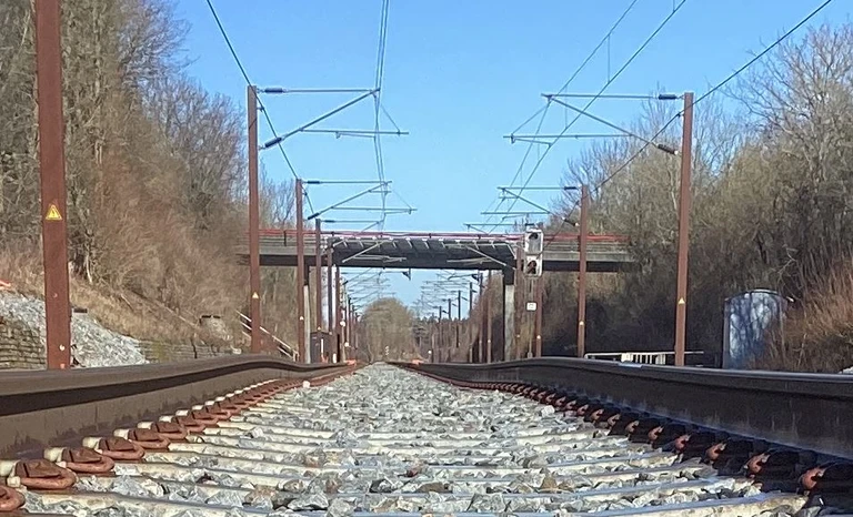 På billedet ses et jernbanespor. Billedet er taget midt i sporet fra et perspektiv omtrent i samme højde som skinneoverkanten. Billedet viser sporets forløb. På både venstre og højre skinnes forløb ses tydeligt en hævning. Hævningen er størst på skinne i venstre side af billedet.