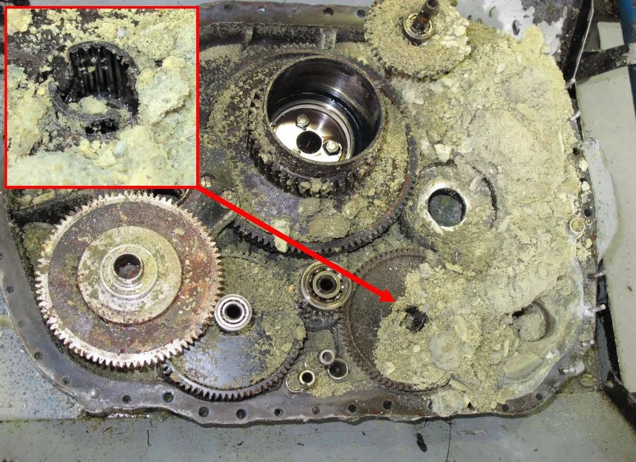 One half of the split opened accessory gearbox with a greenish powdery substance and a fractured drive shaft coupling to the oil pump gearshaft