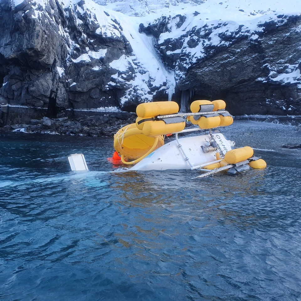 The helicopter on its LH side close to the shore