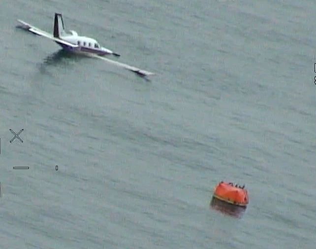 The figure shows D-EOSE floating on the surface with the pilot and the passenger onboard the life raft.