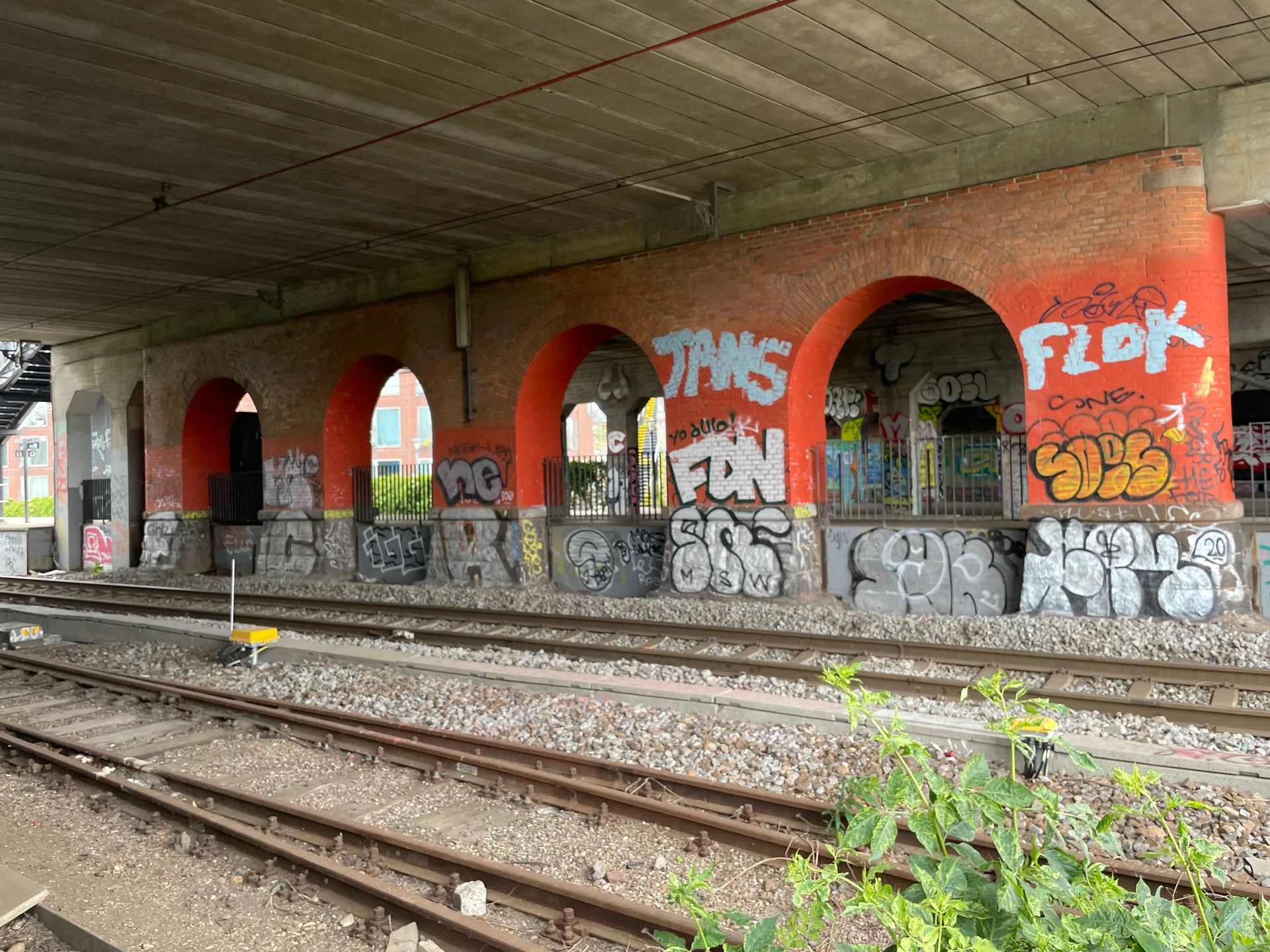 Billedet viser spor 11 under broen. Ved siden af sporet ses murede søjler med buer, der understøtter broen. Imellem buerne er der opsat rækværk. Yderst til venstre på billedet, kan bagkanten af perronen ses.