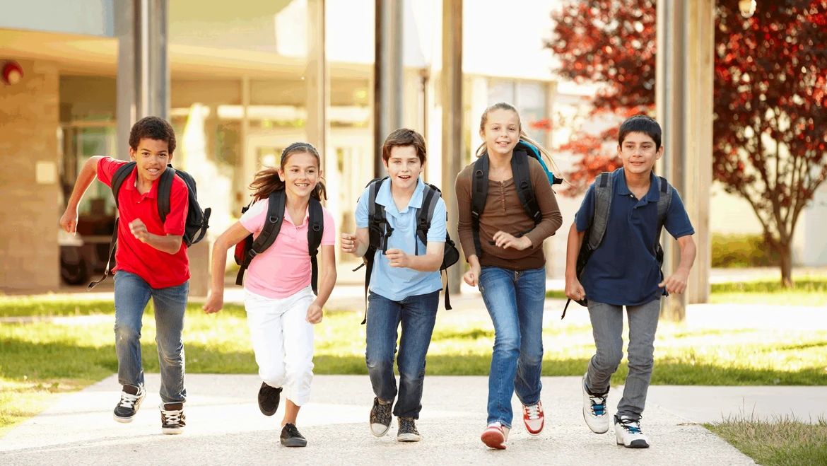 Fem børn med skoletaske løber én i møde