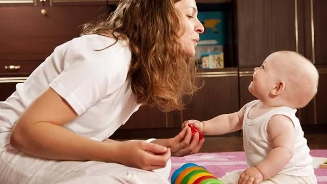 Kvinde sidder og leger med et lille barn