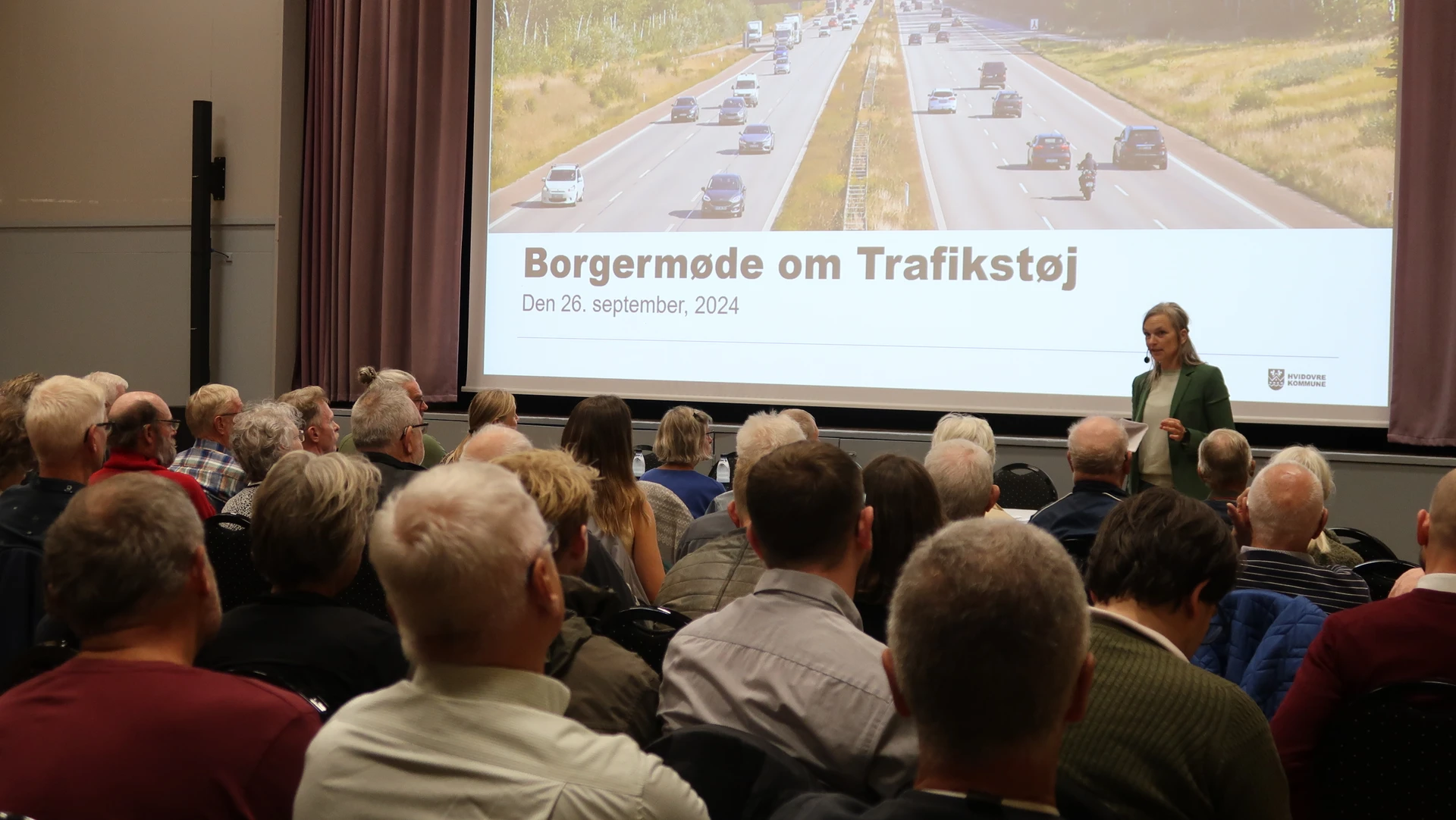 Billede fra borgermødet om trafikstøj, hvor Støjudvalgets formand, Kristina Young, byder velkommen.
