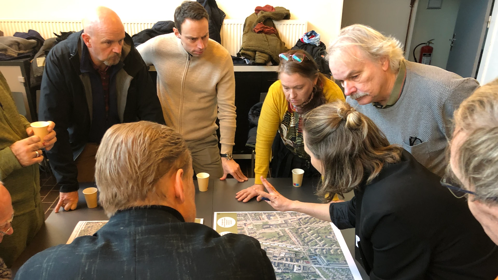 Borgere og politikere omkring et bord med luftfotos til workshoppen om Høvedstensvej-området