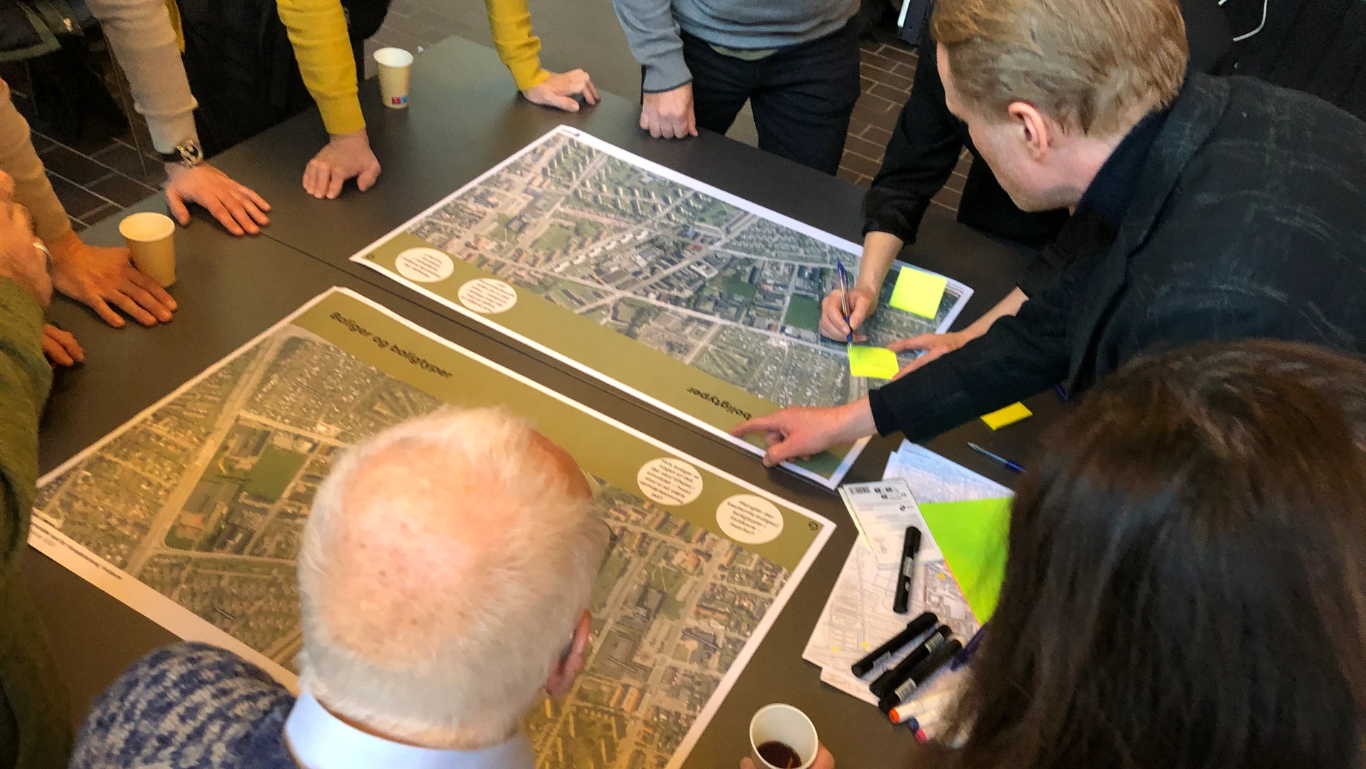 Borgere kigger på et luftfoto til workshop om udvikling af Høvedstensvej-området.