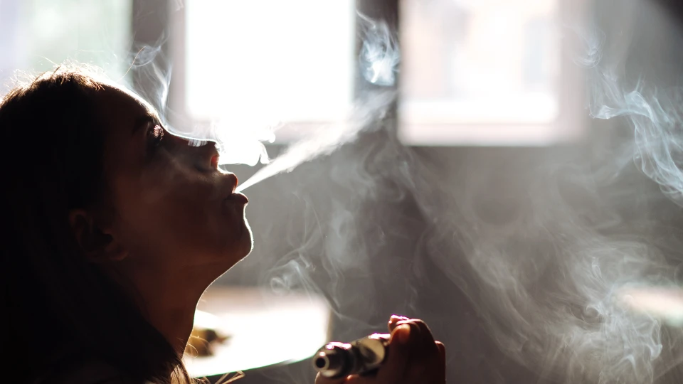 Ung kvinde puster damp fra en e-cigaret