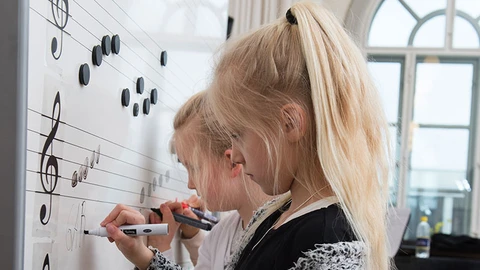 Piger skriver noder på tavle