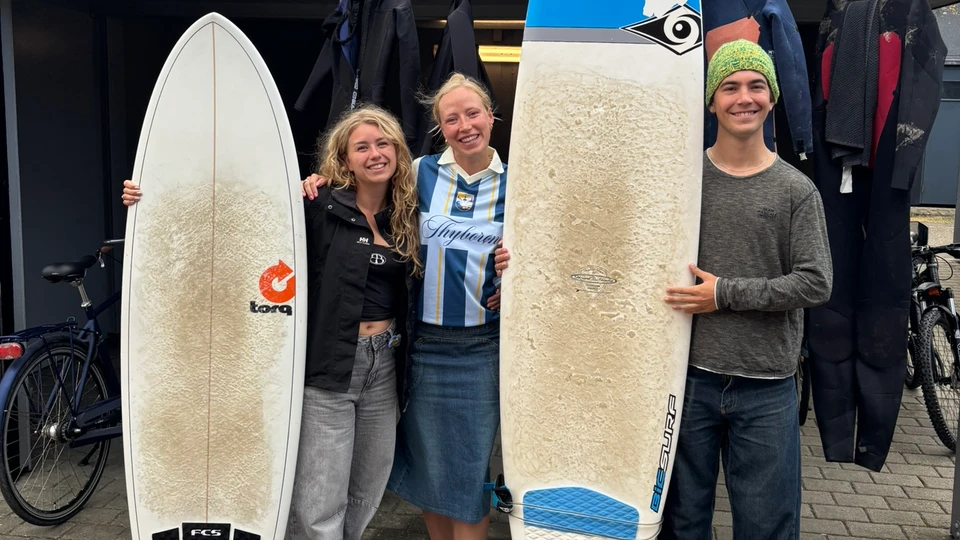 Tre unge mennesker med surfboards