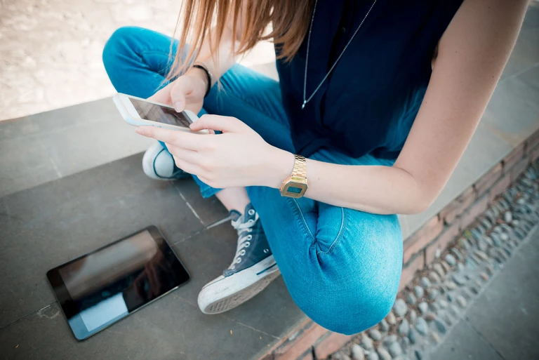 Et barn sidder med sin telefon