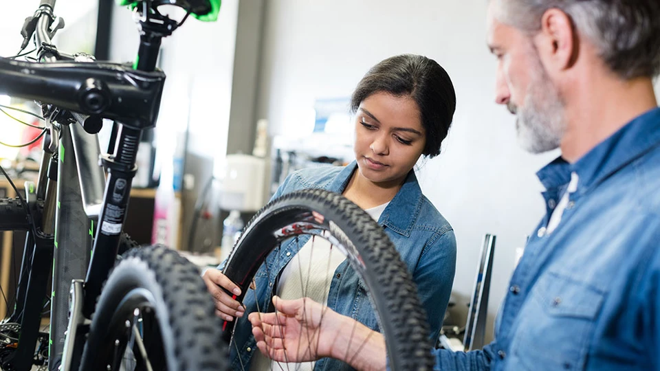 Ung kvinde lærer at reparere en cykel