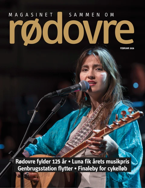 Forside af magasinet, hvor en kvinde spiller guitar og synger ind i mikrofon.  