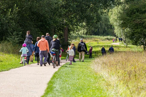 Børn og voksne går og cykler ned af en sti