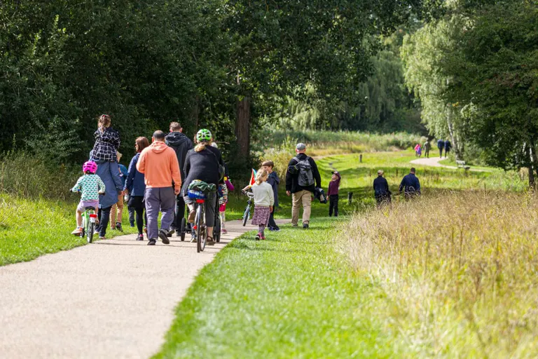 Børn og voksne går og cykler ned af en sti
