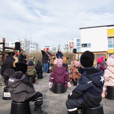Børn sidder på spande og lytter til musik