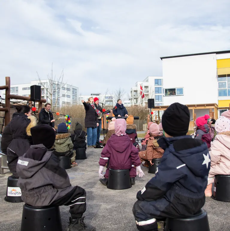 Børn sidder på spande og lytter til musik