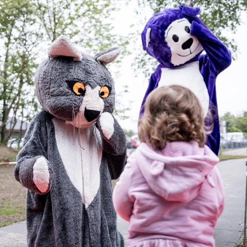 To voksne klædt ud som en mus og en bamse samt et barn med ryggen til kameraet