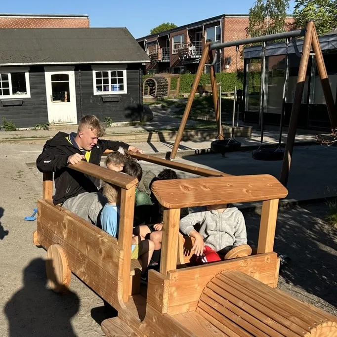 Børn og voksen leger bus