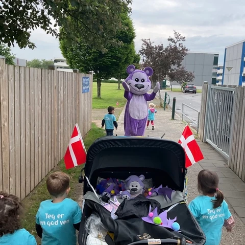 Børn går med barnevogn og møder en stor bamse